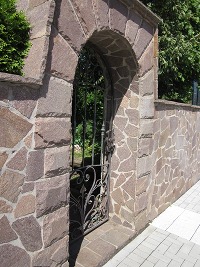 Grundstückseinfriedung mit Torbogen in Südtiroler Porphyr